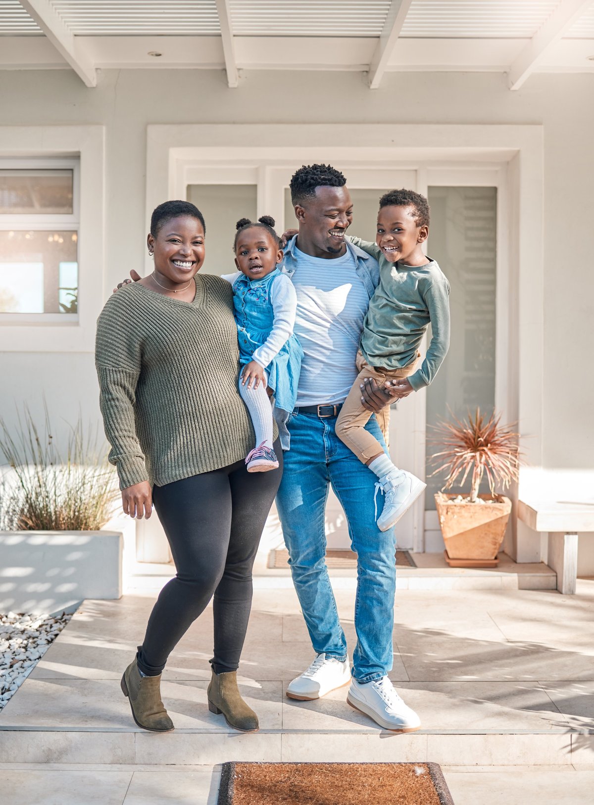 Happy relieved family smiling together in front of their suburban home